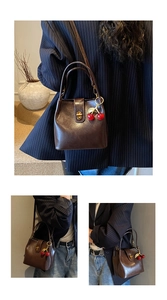 Detail of dark brown vintage bucket bag with wax leather texture and cherry charm