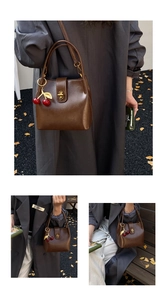 Detail of vintage brown leather bucket bag featuring a cherry charm and metallic turn-lock