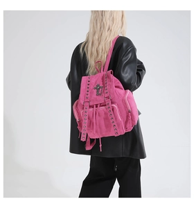 Detailed back view of a pink suede backpack with metal rivets and gothic cross chains
