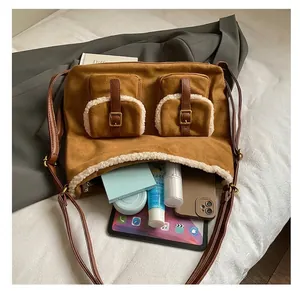 Macro view of a large brown suede shoulder bag showing spacious interior with tablet and tools