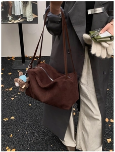 Detail of dark brown suede tote bag with zipper and cute teddy bear doll pendant