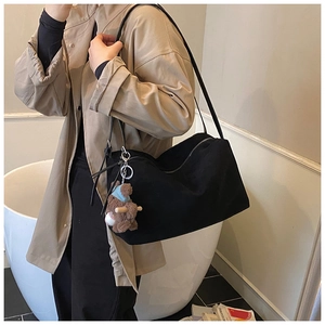 Detail of black canvas tote bag with a cute brown bear charm and smooth zipper closure