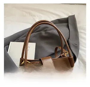 Detail of vintage brown bucket bag featuring a gold square lock and cherry charm accessory