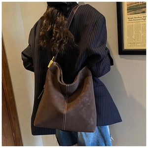 Detail of coffee brown suede tote bag with contrast white stitching and gold buckle