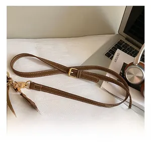 Detail of adjustable brown leather shoulder strap with gold buckle and white stitching