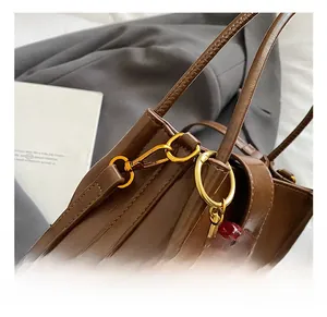 Detail of vintage brown leather handbag with gold hook and red cherry pendant