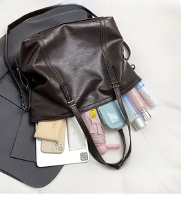 Top view of spacious interior of brown leather tote bag with various daily essentials