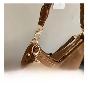 Detail of gold-tone metal hooks and white stitching on a brown leather tote bag