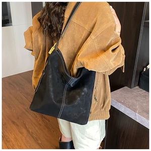 Detail of vintage black suede bucket bag featuring white contrast stitching and long strap
