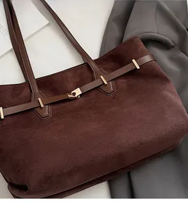 Détail du sac cabas en daim chocolat avec poignées en cuir marron et boucles en métal doré