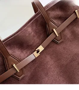 Détail d'un sac cabas marron vintage avec serrure rotative dorée et texture daim