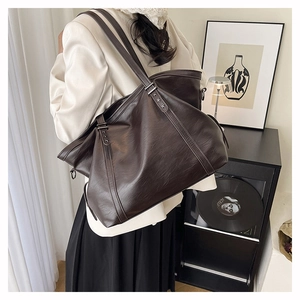 Detail of large brown tote bag on shoulder featuring metallic star accents and soft leather