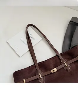 Détail du sac fourre-tout en daim marron foncé avec bandoulière et boucle métallique
