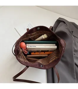 Intérieur spacieux du sac cabas en daim marron foncé avec doublure à rayures et objets