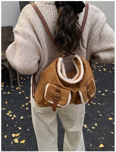 Brown suede backpack with white faux fur trim shown on a model in an autumn setting