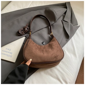 Detail of vintage brown suede hobo bag with gold hardware and adjustable strap on blazer