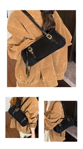 Detail of adjustable gold buckle on black oil wax leather shoulder baguette bag