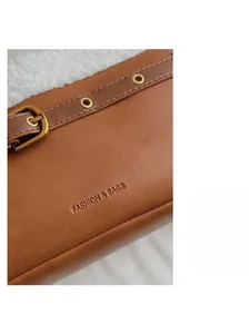 Detail view of brown leather bag with white faux fur trim and brass buckle