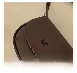 Gros plan sur la texture en cuir marron foncé avec logo COTH ZPN embossé sur le sac
