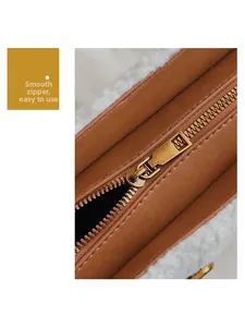 Detail of smooth metal zipper and white faux fur texture on brown leather shoulder bag
