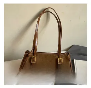 Detail view of brown shoulder bag showing suede stitching, gold buckles, and fringe zipper