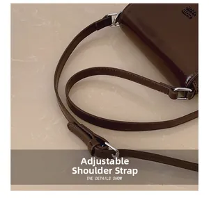 Détail de la bandoulière réglable sur le sac en cuir brillant marron foncé