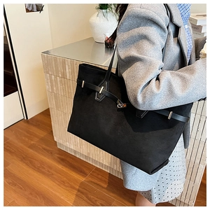 Détail du grand sac cabas noir en daim avec sangle décorative et boucle argentée à l'épaule