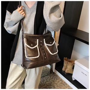 Detail of dark brown faux leather crossbody bag with faux fur trim and dual front pockets