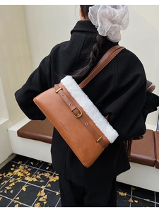Detail of brown PU leather shoulder bag with white faux fur trim and belt buckle accent