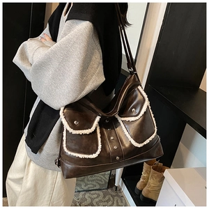 Detail of brown faux leather shoulder bag featuring plush fleece trim and silver studs