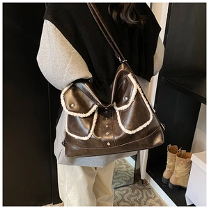 Detail of vintage brown leather tote bag featuring white fleece trim and silver rivets