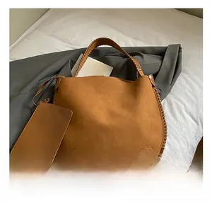 Detail view of brown hobo bag and matching coin purse with woven stitching on white bedding