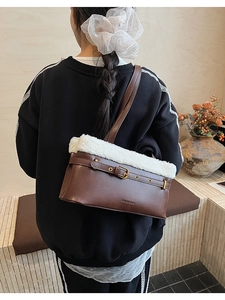 Close-up of brown leather shoulder bag featuring white plush trim and buckle detail