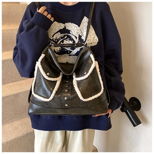Detail of black tote bag with white shearling trim and silver studs on a female model