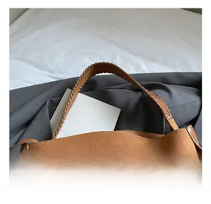 Close-up of coffee brown suede tote bag featuring detailed woven handle and large capacity