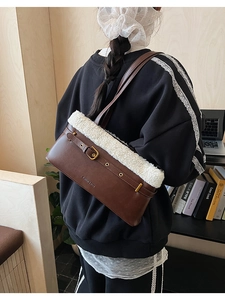 Detail of a brown leather shoulder bag featuring plush white faux fur trim and belt buckle