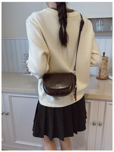 Sacoche marron foncé en cuir brillant portée par un mannequin dans un cadre cosy