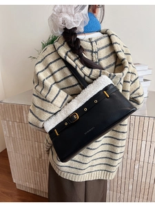 Detail of plush lamb wool trim and black pebble leather texture on stylish handbag