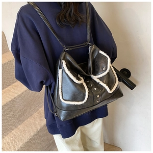 Close-up of black PU leather bag with white fleece trim and silver rivet accents