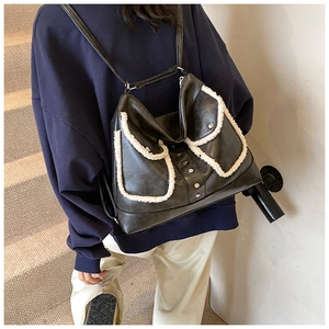 Detail of black PU leather backpack featuring white faux shearling trim and metal rivets