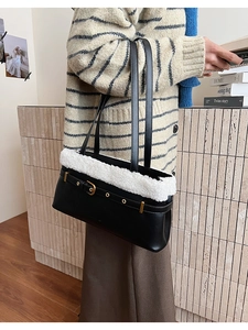 Detail of black faux leather tote bag with white faux fur trim and gold buckle decor