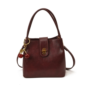 Retro burgundy leather bucket bag with gold twist lock and cherry charm accessory