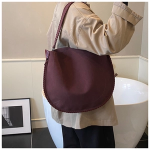 Detail of burgundy hobo shoulder bag with matte texture and woven stitching details