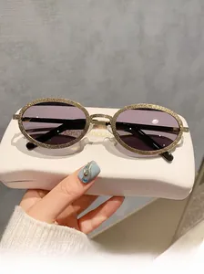 Détail de lunettes de soleil ovales en métal avec monture dorée et verres violets