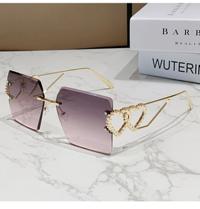 Détail de lunettes de soleil sans monture avec verres dégradés roses et cœurs dorés