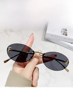 Close-up of rimless oval sunglasses with grey lenses and crystal F detail on temples