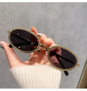 Détail de lunettes de soleil ovales avec texture pailletée dorée et verres teintés