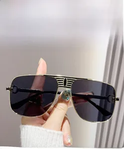 Gros plan de lunettes aviateur dorées avec verres gris et détail de double pont