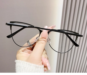 Détail de la monture de lunettes demi-cerclée noire style yeux de chat tenue à la main