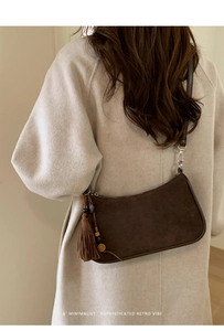 Detail of dark brown suede shoulder bag featuring long tassels and wooden bead charm